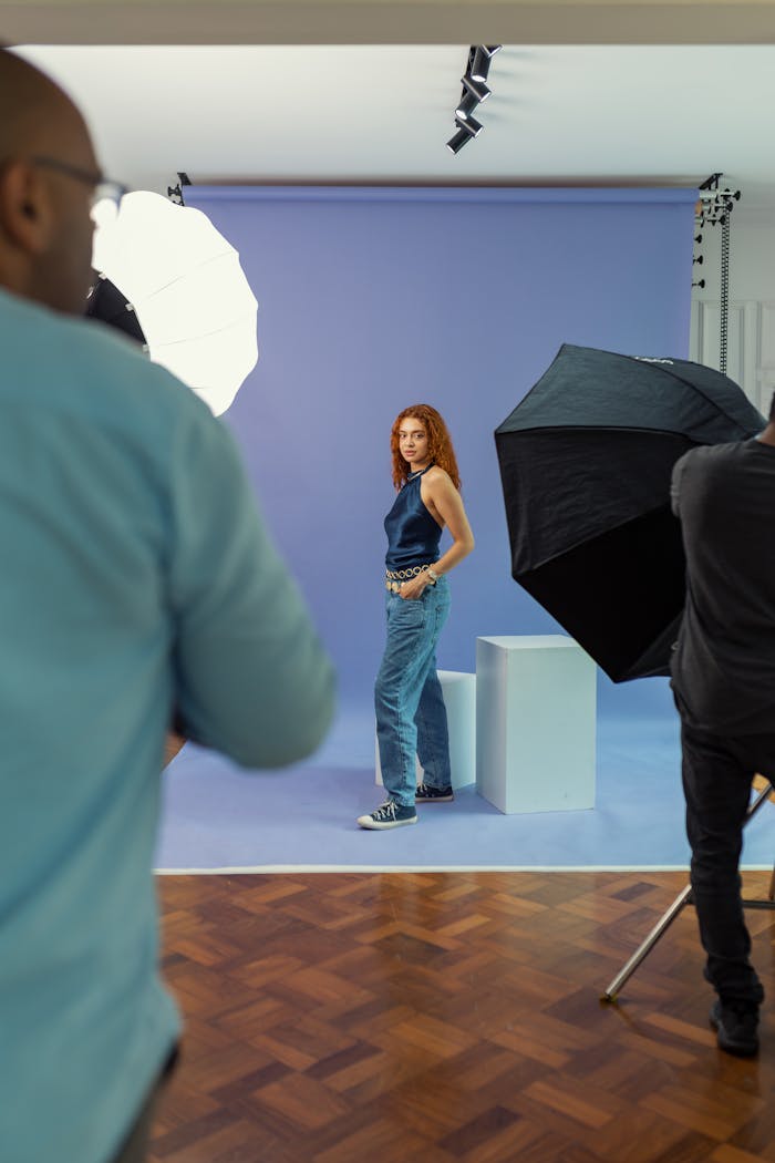 Photographer captures a model posing in a professional studio with lighting equipment.